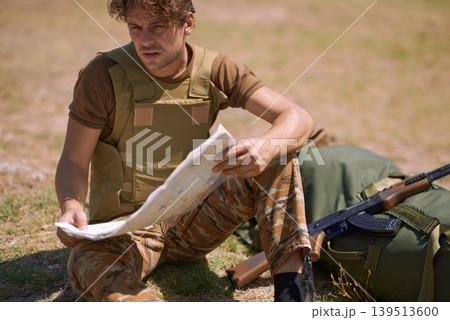 Soldier with map outdoor, planning battle route or tactical operation goals for mission in war. Man on battlefield or at military base camp, check strategy paperwork with army target and attack 139513600