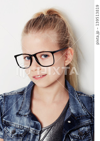 Child, portrait and cool fashion glasses in studio, frame and confident by white background. Female person, girl and casual clothing or style by backdrop, kid and denim jacket pride for eyesight test 139513819