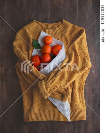 Sweater with a bag of tangerines. 139513833
