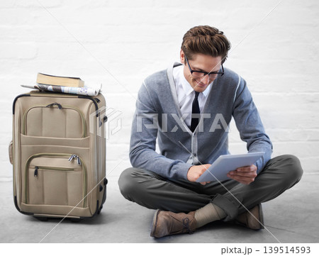Business man, reading or luggage with tablet, floor and smile with app, flight or travel by wall background. Entrepreneur, person or employee with digital touchscreen, bag and happy for immigration 139514593