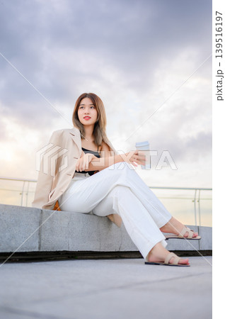 successful asian businesswoman holding a takeaway coffee cup outside of the office building  139516197