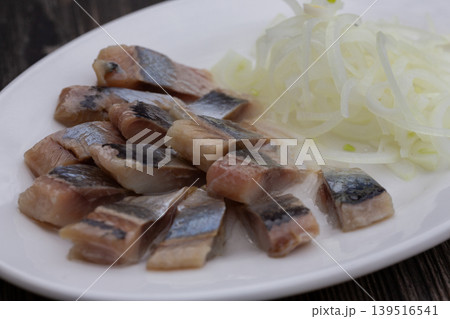 Salted herring with onions on a white plate, the perfect appetizer for vodka. 139516541