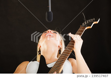 Woman playing on electric guitar and singing Woman playing on electric guitar and singing 139517407