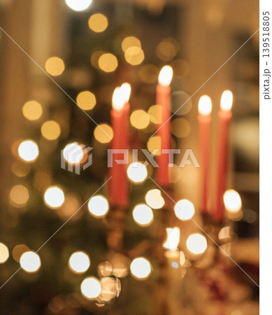 Candles with red holders illuminated in soft focus, surrounded by blurred lights of a decorated Christmas tree in a cozy indoor setting Candles with red holders illuminated in soft focus, surrounded by blurred lights of a decorated Christmas tree in a cozy indoor setting 139518805