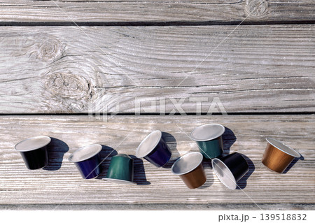 Multicolo red coffee capsules are scattered on the light wooden surfac 139518832