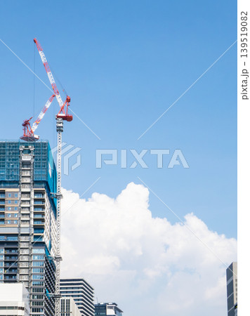 青空に向かって伸びる建設中の高層ビルとクレーン 139519082