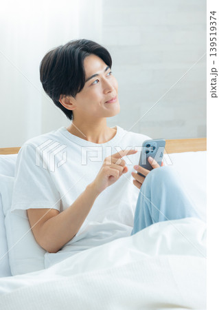 朝スマホを見て悩む男性 朝スマホを見て悩む男性 139519374