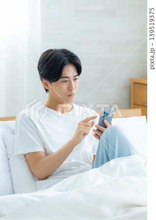 朝スマホを見て悩む男性 朝スマホを見て悩む男性 139519375