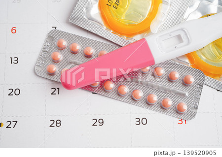 Pregnancy test with birth control pills and condom for female on calendar, ovulation day. 139520905