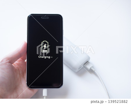 電池残量僅かのスマホにモバイルバッテリーを接続して充電する様子(画面デザインはオリジナル制作) 電池残量僅かのスマホにモバイルバッテリーを接続して充電する様子(画面デザインはオリジナル制作) 139521882