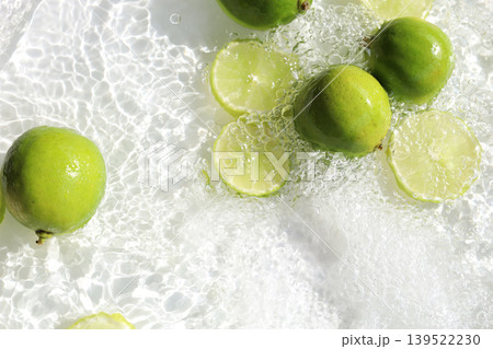 Fresh green lime slices floating in clear water with ripples texture. Fresh green lime slices floating in clear water with ripples texture. 139522230