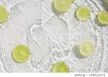Fresh green lime slices floating in clear water with ripples texture. Fresh green lime slices floating in clear water with ripples texture. 139522231