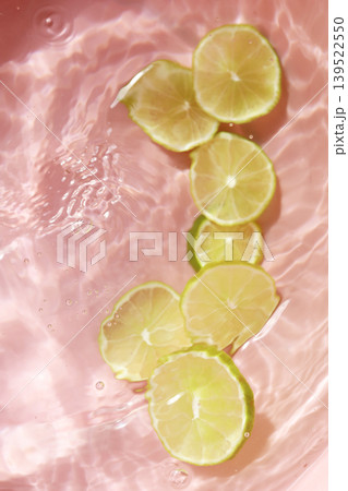 Fresh green lime slices floating in clear water with ripples texture. Fresh green lime slices floating in clear water with ripples texture. 139522550