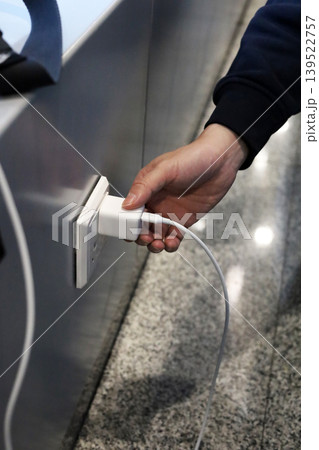 Plugging phone charger into wall outlet Plugging phone charger into wall outlet 139522757