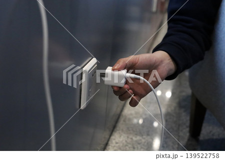 Hand plugging charger into wall socket Hand plugging charger into wall socket 139522758
