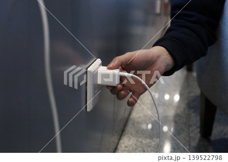 Hand plugging charger into wall socket Hand plugging charger into wall socket 139522798