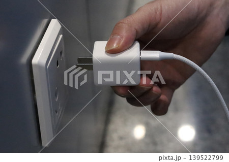Hand plugging charger into wall socket 139522799