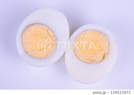 Eggs on lavender. Closeup of halved eggs with vibrant yolks on lavender setting. Detailed view of cut boiled eggs featuring vivid yolks against soothing lavender surface 139523972
