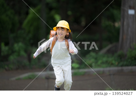 新緑の中ランドセルで走る登校する笑顔の女の子 黄色い帽子を被った1年生の新生活と通学や学校、学資保険 新緑の中ランドセルで走る登校する笑顔の女の子 黄色い帽子を被った1年生の新生活と通学や学校、学資保険 139524027