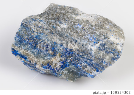 Lapis lazuli slab with glittering pyrite rich ultramarine pockets rough polished edges and tactile texture ideal for artisan pigment or jewelry cutting in warm studio mood 139524302