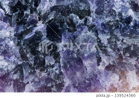 Close examination highlights dark mineral pockets and vivid textures. Detailed shot showcasing coarse crystalline grains and intense color contrasts in amethyst matrix Close examination highlights dark mineral pockets and vivid textures. Detailed shot showcasing coarse crystalline grains and intense color contrasts in amethyst matrix 139524360