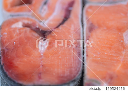 Market display features icy salmon portions. Rustic style with frosted seafood at counter. Handcut frozen salmon pieces showcased at market with rustic display and icy glaze Market display features icy salmon portions. Rustic style with frosted seafood at counter. Handcut frozen salmon pieces showcased at market with rustic display and icy glaze 139524456