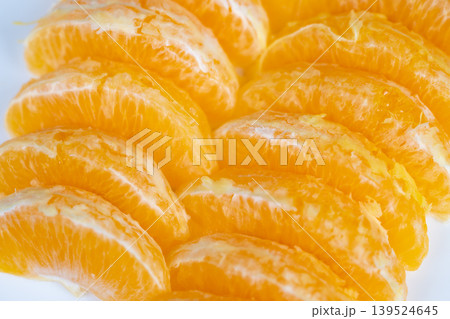 Photographic depiction of glossy orange segments with delicate membranes visible. Aesthetic arrangement of shiny orange slices showcasing fine membranes in warm inviting tones 139524645