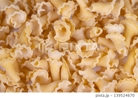 Rustic pasta with textured surface. Closeup view of artisanal pasta textures and colors. Fine details of rustic semolina pasta with golden hues and ruffled edges Rustic pasta with textured surface. Closeup view of artisanal pasta textures and colors. Fine details of rustic semolina pasta with golden hues and ruffled edges 139524670