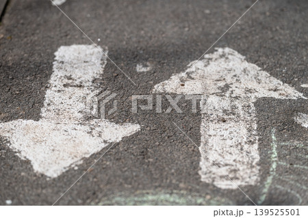 Faded directional markings. Eroded symbols indicate travel directions distinctly. Worn directional pavement symbols illustrate choice paths for walkers and bikers clearly 139525501