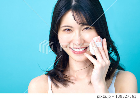 笑顔でパフを頬に当てる若い日本人女性のクローズアップ 139527563