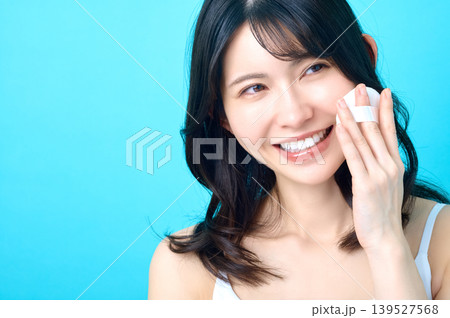 横を見て歯を見せて笑顔でパフを頬に当てる若い日本人女性 139527568