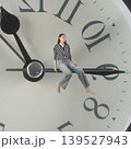 Woman sitting on clock hand losing concept of time 139527943