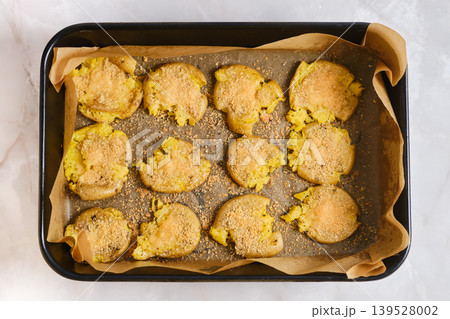 Crispy smashed potatoes on a baking sheet ready for serving at a casual dining event 139528002
