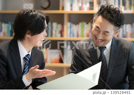 本棚のある社長室で決算報告書を見ながら相談、ビジネスマンの打ち合わせ成長と提案　などの会計士や士業 139528491