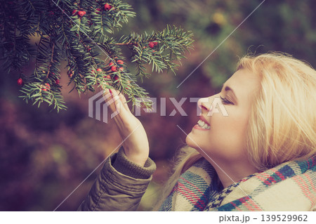 Woman dressed warmly looking at bush Woman dressed warmly looking at bush 139529962