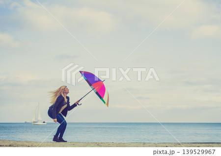 Woman jumping with colorful umbrella on beach 139529967