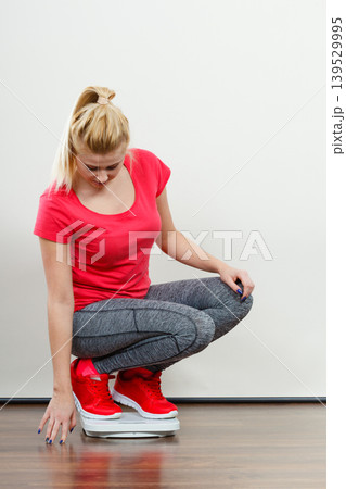 Woman wearing sportswear standing on weight machine 139529995