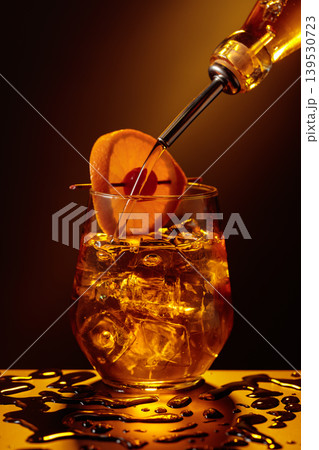 Old fashioned cocktail in a sweating glass on a wet black table. Old fashioned cocktail in a sweating glass on a wet black table. 139530723
