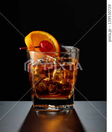 Old fashioned cocktail in a sweating glass on a black table. Old fashioned cocktail in a sweating glass on a black table. 139530729