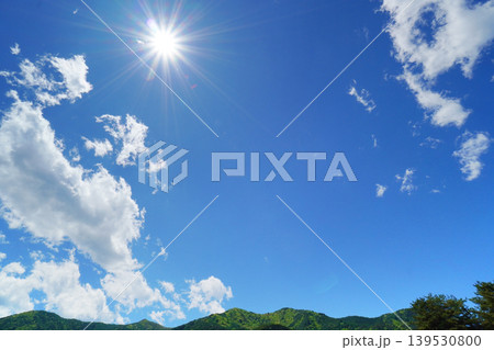 ギラギラ輝く太陽と少し雲のある爽やかな青空と山の風景 139530800