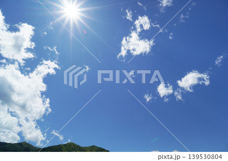 ギラギラ輝く太陽と少し雲のある爽やかな青空と山の風景 ギラギラ輝く太陽と少し雲のある爽やかな青空と山の風景 139530804