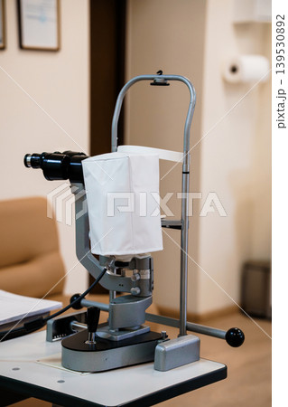 Ophthalmic surgical microscope used for eye operations with white drape in medical clinic room interior Ophthalmic surgical microscope used for eye operations with white drape in medical clinic room interior 139530892