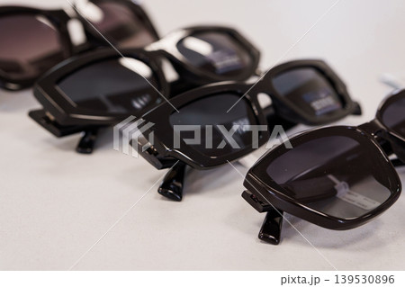 Collection of black retro sunglasses stacked neatly on white table for summer fashion accessory concept Collection of black retro sunglasses stacked neatly on white table for summer fashion accessory concept 139530896
