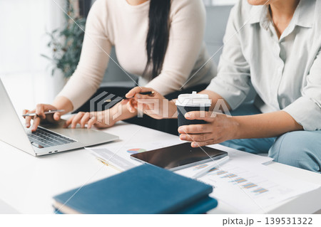 Close-up of two women reviewing reports, using a laptop and tablet at home, illustrating budget planning, financial analysis, online consultation, teamwork and modern remote work lifestyle. 139531322