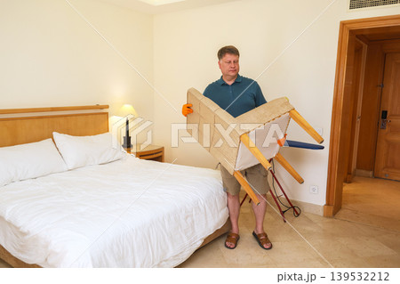 A man moves furniture to a new location in his spacious bedroom A man moves furniture to a new location in his spacious bedroom 139532212