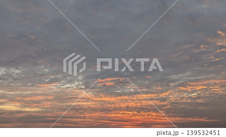 Vibrant orange sunrise light illuminates dark, textured clouds in the morning sky. This dramatic landscape captures natural beauty, atmospheric transitions, scenic outdoor views during dawn hours. Vibrant orange sunrise light illuminates dark, textured clouds in the morning sky. This dramatic landscape captures natural beauty, atmospheric transitions, scenic outdoor views during dawn hours. 139532451
