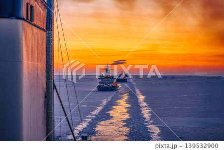 Icebreaker convoy navigating frozen sea at sunset Icebreaker convoy navigating frozen sea at sunset 139532900