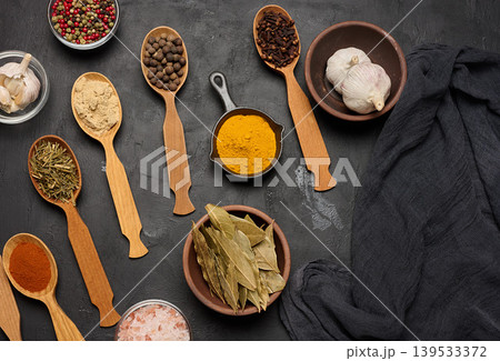 Various ground spices in wooden spoons, peppercorns on dark table Various ground spices in wooden spoons, peppercorns on dark table 139533372