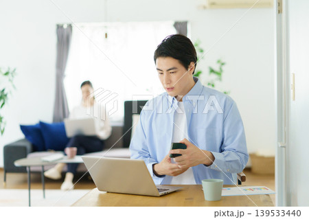 自宅のテーブルでノートパソコンで仕事をする若い日本人男性 自宅のテーブルでノートパソコンで仕事をする若い日本人男性 139533440