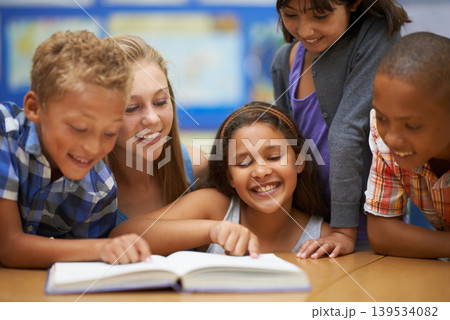 Children, teacher and reading a book in classroom for knowledge, learning or education with happiness. Group, student and woman at school with study, textbook and smile with diversity at college Children, teacher and reading a book in classroom for knowledge, learning or education with happiness. Group, student and woman at school with study, textbook and smile with diversity at college 139534082